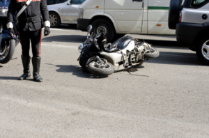 Motorcycle lying on the road after an accident with police officer standing nearby